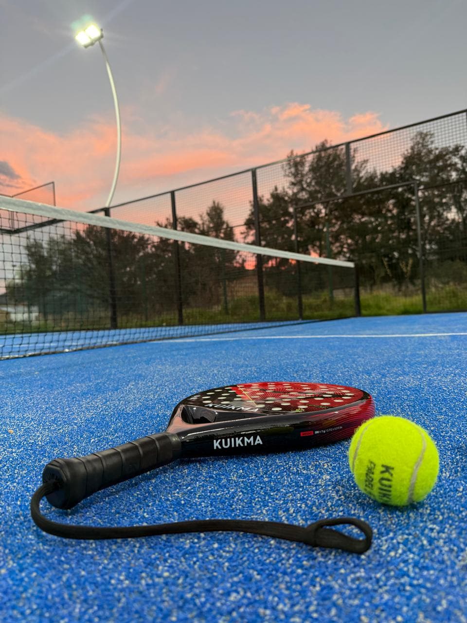 Pala y pelota sobre la cancha al atardecer