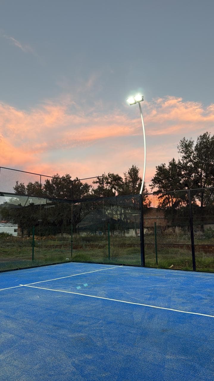 Cancha bajo un cielo de atardecer con el reflector encendido